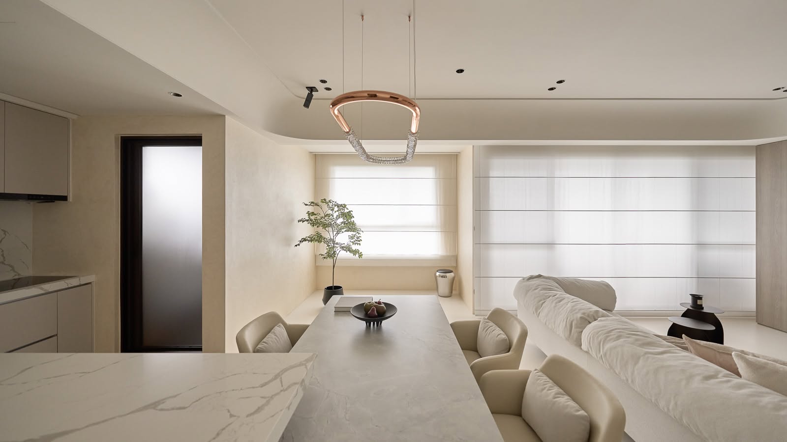 Open living and dining space in soft beige tones with a sculptural pendant light