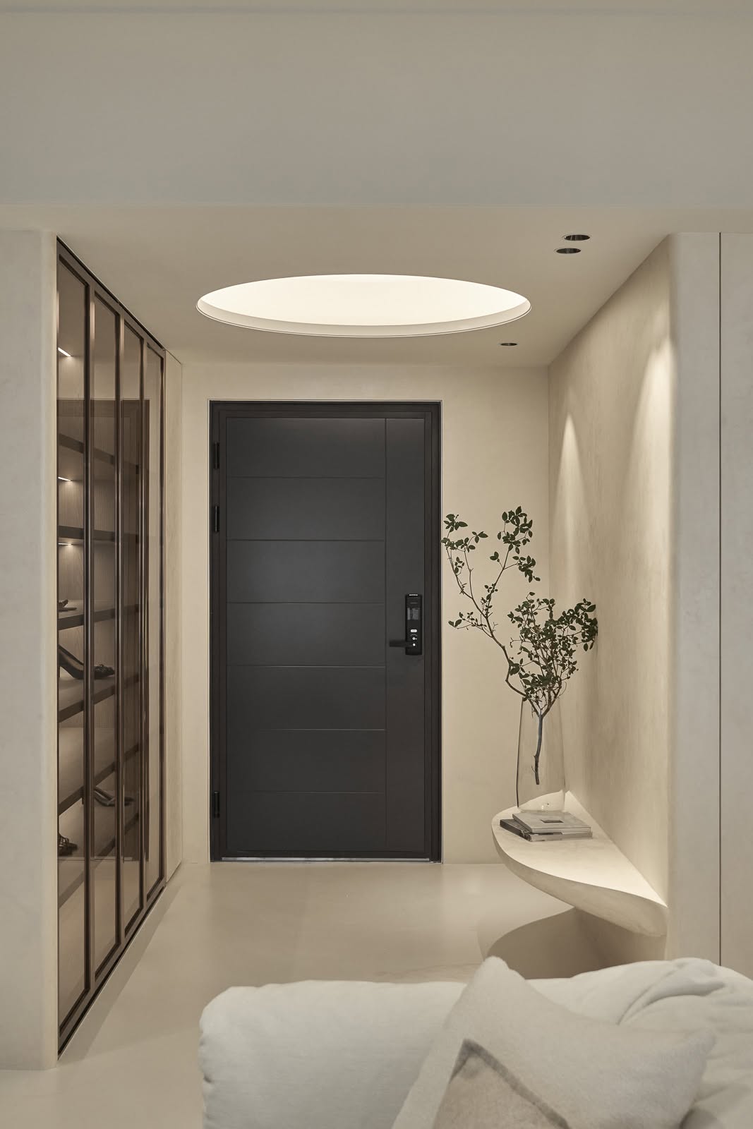 Minimalist entrance foyer with warm plaster walls and a black feature door